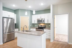Contemporary kitchen with sleek stainless steel appliances, elegant granite countertops, white cabinets, and inviting hardwood floors.