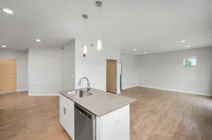 Spacious open-concept living area with modern kitchen, featuring sleek countertops and elegant lighting.