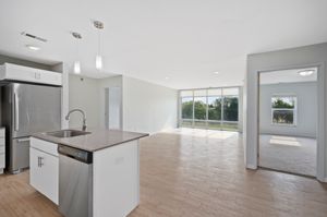 Bright and airy open-plan apartment featuring a modern kitchen with stainless steel appliances, spacious living area, and floor-to-ceiling windows offering scenic views.