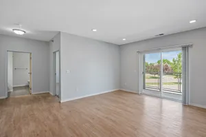 Bright and airy living space with large sliding glass doors leading to a balcony, featuring modern hardwood floors and soft gray walls.