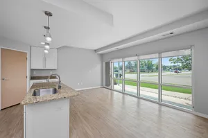 Bright, open-concept living and kitchen area with large windows, stylish pendant lighting, and modern fixtures.