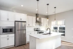 Modern kitchen with sleek white cabinetry, stainless steel appliances, and elegant pendant lighting over a central island.