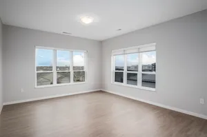 Bright room with large windows offering scenic views, featuring sleek hardwood floors and soft neutral walls, ideal for a modern living area.