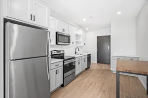 Modern kitchen with sleek stainless steel appliances, white cabinetry, and elegant wood flooring.