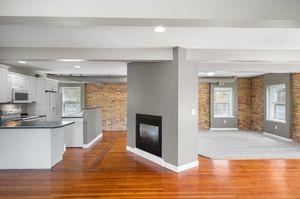 Charming open-concept living space with hardwood floors, modern kitchen, and exposed brick accents.