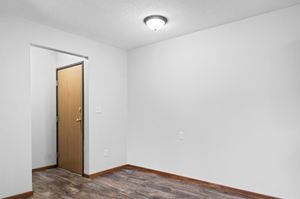 Inviting entryway with wooden door and sleek laminate flooring, offering a warm welcome to a modern apartment.