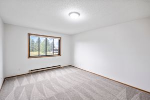 Bright and inviting room with plush carpet, large window offering scenic views, and ample natural light.