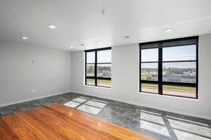 Bright and spacious living area with large windows offering scenic views, featuring modern flooring and a fresh, contemporary design.