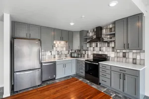 Modern kitchen with sleek grey cabinetry, stainless steel appliances, and elegant tiled backsplash.
