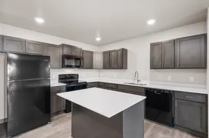 Modern kitchen with sleek dark cabinetry, integrated appliances, and a spacious island countertop offering elegance and functionality.