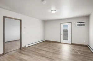 Bright, open-concept living room with elegant wood flooring, access to a private balcony, and modern finishing touches.