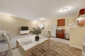 Modern open-plan living area with cozy seating, dining set, and compact kitchen.