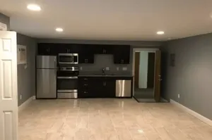 Modern kitchen with sleek stainless steel appliances, tiled flooring, and stylish dark cabinetry.