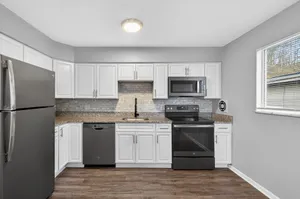 Contemporary kitchen with stainless steel appliances, sleek granite countertops, and elegant white cabinetry, featuring a cozy window view.