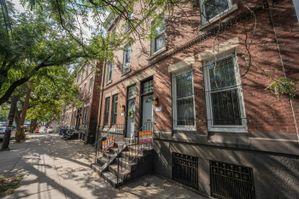 Charming street view of a historic brick apartment building with beautiful trees and inviting entryway.