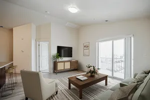 Bright and inviting living room with modern decor, featuring a cozy sofa, stylish coffee table, and large sliding glass doors leading to the balcony.