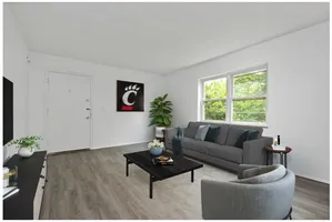 Bright and airy living room with modern decor, featuring a comfortable gray sofa, a sleek coffee table, and large windows with green views.