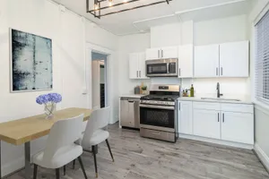 Modern kitchen with sleek white cabinets, stainless steel appliances, and a stylish dining area.