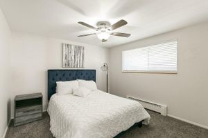 Elegant bedroom with plush navy headboard, modern ceiling fan, and chic decor, offering a serene and inviting atmosphere.