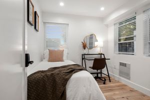 Inviting bedroom with a single bed, decorative pillows, and a modern workspace.