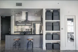 Modern kitchen with sleek countertops, stylish backsplash, and elegant storage solutions. Features stainless steel appliances and a cozy bar area with two stools.