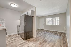 Modern kitchen and living area with open layout, featuring sleek appliances and wood flooring.