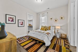 Inviting bedroom with colorful rug, elegant wall art, and cozy decor, blending comfort and style seamlessly.