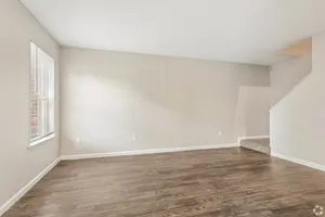 Bright living room with staircase and wood-style flooring at Shadowbrook Townhomes in Memphis, TN