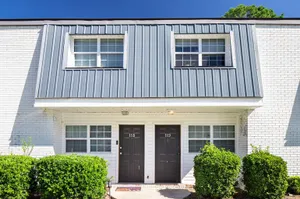 Charming townhouse exterior with sleek metal roofing, classic brick facade, and inviting front entry.