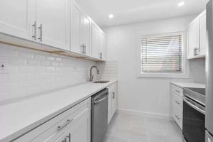 Sleek and modern kitchen featuring white cabinetry, stainless steel appliances, and a bright, airy atmosphere.
