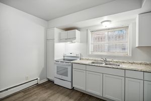 Bright, modern kitchen with sleek white cabinetry, granite countertops, and ample natural light through a large window.