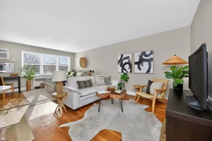 Inviting living room with abundant natural light, cozy seating, modern art, and stylish decor.