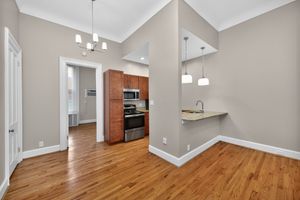 Charming apartment kitchen with sleek wooden cabinetry, elegant granite countertops, and modern stainless steel appliances. Features inviting hardwood floors and chic pendant lighting.