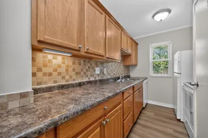 Modern kitchen with warm wooden cabinetry, sleek countertops, and a bright window view.