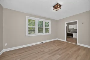 Bright, open living space with large windows and modern kitchen featuring stainless steel appliances.