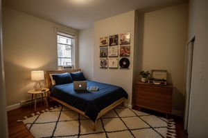 Cozy bedroom with a modern aesthetic, featuring a wooden bed, stylish decor, and inviting ambiance, perfect for relaxation.