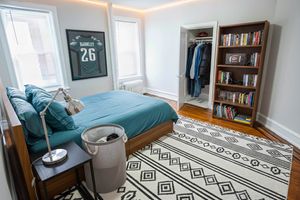 Bright and cozy bedroom featuring a blue-themed decor, sleek lighting, and a stylish wall art piece. Includes a spacious bookshelf and organized closet for optimal storage.