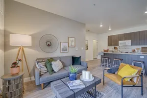 Chic open-concept living room with modern decor and cozy seating, seamlessly flowing into a stylish kitchen with bar seating.