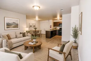 Bright and inviting open-concept living area featuring a cozy sofa, elegant dining set, and modern kitchen with wood flooring and stylish decor.