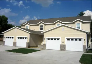 Charming townhouse with multiple garages, featuring elegant architecture and a neatly maintained exterior under a clear blue sky.