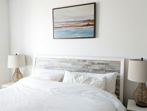 Cozy bed with matching nighstands and painting of coast on wall