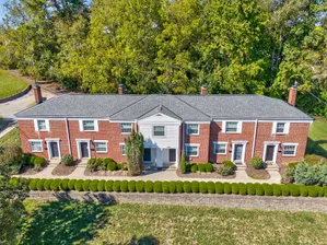 Charming brick apartment complex nestled among lush greenery, featuring classic architecture and well-maintained landscaping for a serene living environment.