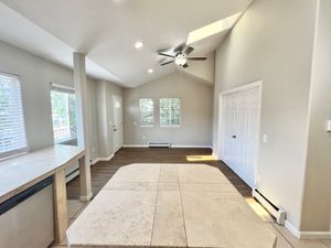 Open-concept living space with tiled flooring, large windows, and ceiling fan, offering ample natural light.