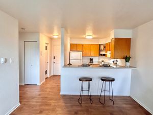 Contemporary apartment kitchen with wooden cabinets, breakfast bar, and elegant wooden flooring.