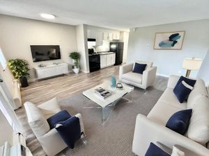 Contemporary living room with sleek white furniture, stylish decor, and an open-plan kitchen, offering a cozy and inviting ambiance.