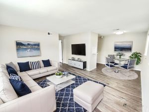 Chic living room with plush white sofas, blue accent pillows, modern decor, and a stylish dining area.