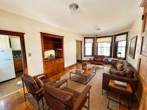 Inviting living room with elegant leather seating, warm wooden accents, and ample natural light from large windows.