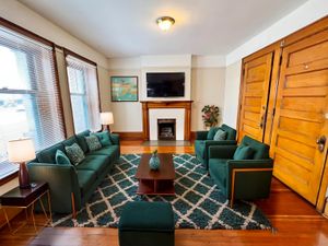 Inviting living room with elegant green sofas, cozy fireplace, and chic wooden accents, perfect for relaxation and entertainment.