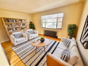 Charming living room with elegant decor, showcasing white furniture, striped cushions, and a cozy ambiance with abundant natural light.