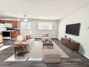 Contemporary open-concept living area with cozy seating, an elegant entertainment center, and a modern kitchen.